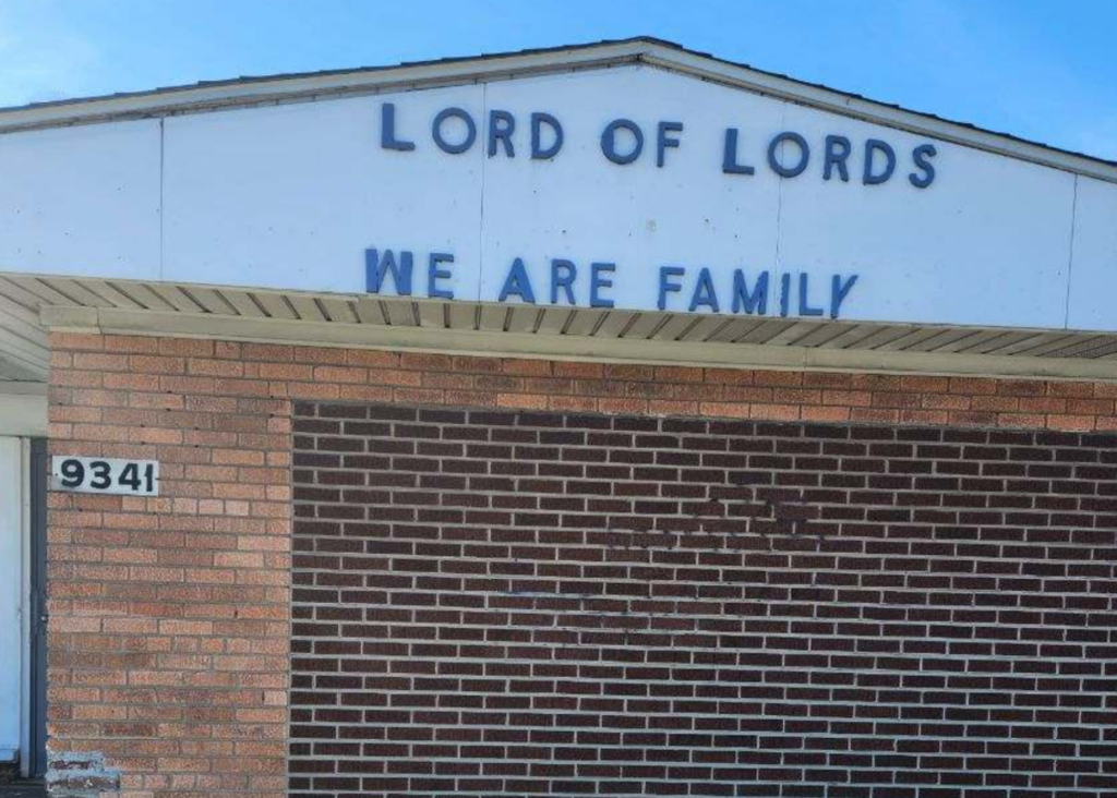 A brick building proudly displays LORD OF LORDS and WE ARE FAMILY in blue letters on its facade, representing the Lord of Lords Ministries. The address 9341 stands out on the left side, with a clear sky providing a serene backdrop.